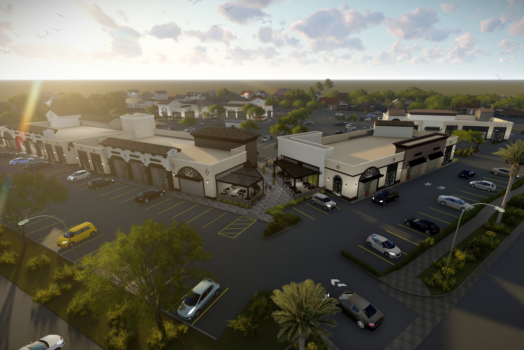 Aerial view of a low contemporary retail center at golden hour, with cream stucco buildings, dark trim and a landscaped parking lot